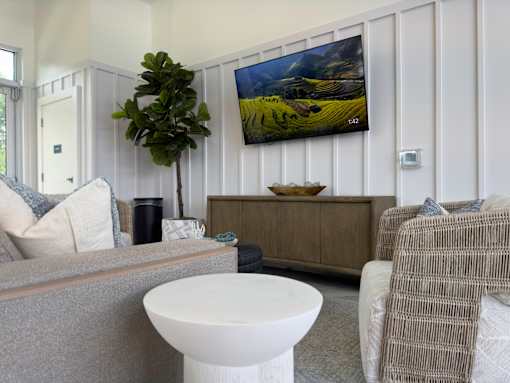 A living room with a grey couch and a television on the wall.