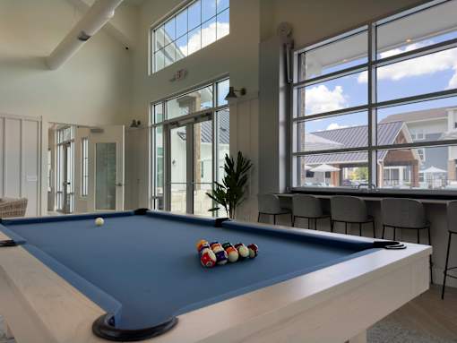 A pool table with a blue cloth and a white cue ball and red, white and blue balls on it.