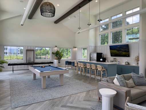 A billiard table is in the middle of a spacious room with a couch and a TV.