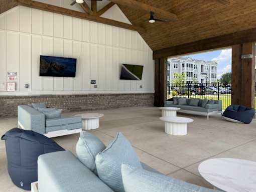 Pet-Friendly Luxury Apartments In Myrtle Beach, SC - Anchor Pointe - A Large Covered Outdoor Lounge With Light Blue Sofas, Bean Bags, And Wall-Mounted Televisions.