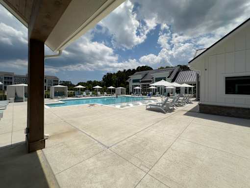 A large outdoor swimming pool with sun loungers and umbrellas.