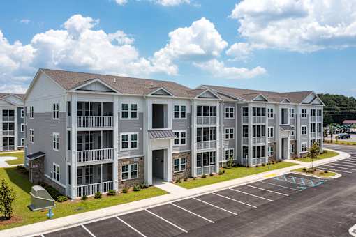 Apartment building with a parking lot in front.