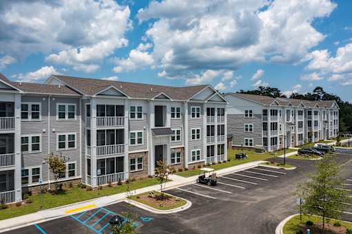 Apartment complex with a parking lot in front.