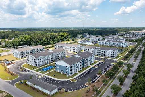 A large apartment complex with a parking lot in front.