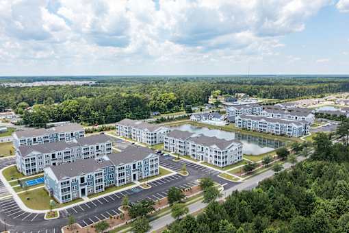 A large, modern apartment complex with a swimming pool and surrounded by greenery.