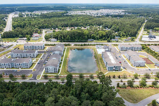 A bird's eye view of a residential area with a large pond in the center.