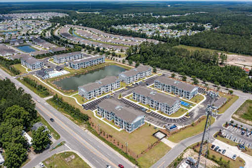 A bird's eye view of a residential complex with a lake in the middle.