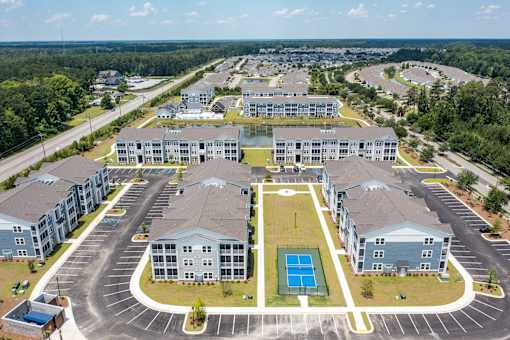 A large, modern apartment complex with a tennis court in the center.