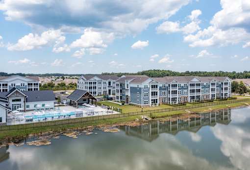 A row of houses are reflected in the water in front of them.
