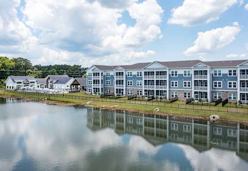 A large building with a grey roof is reflected in the water.