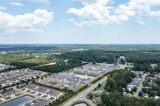 A bird's eye view of a residential area with houses, roads, and a large open field.