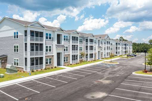 A parking lot in front of a row of apartment buildings.