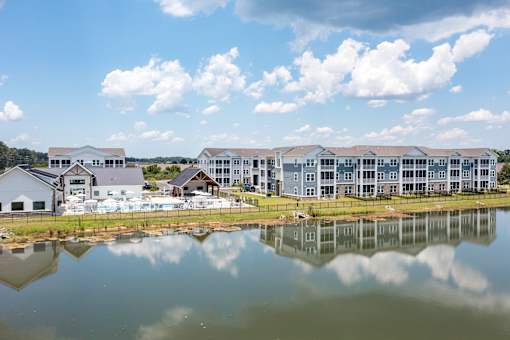 A large building complex is reflected in a body of water.