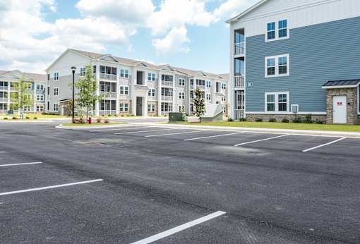 A parking lot in front of a building with a blue building to the right.