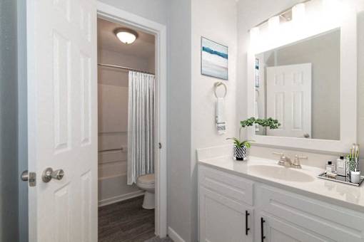 A white bathroom with a toilet, sink, and mirror.