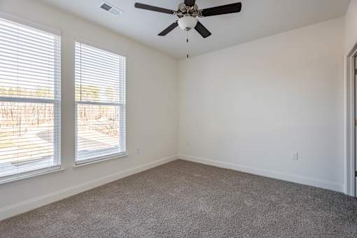 A room with a ceiling fan and carpeted floor.