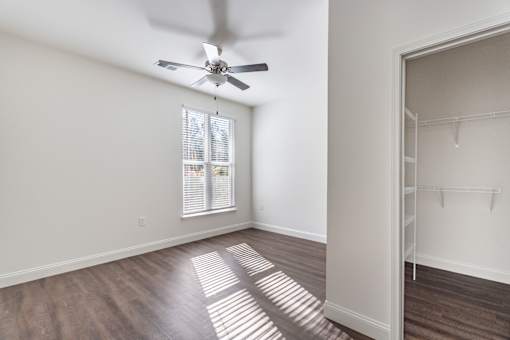 A room with a ceiling fan and a window with blinds.