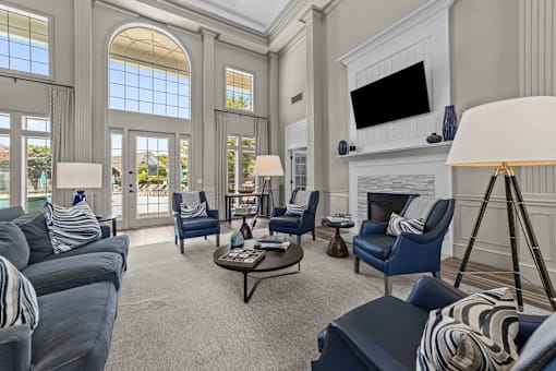 A clubhouse with a grey couch and blue chairs at Heights at New Garden apartments in Greensboro, NC.