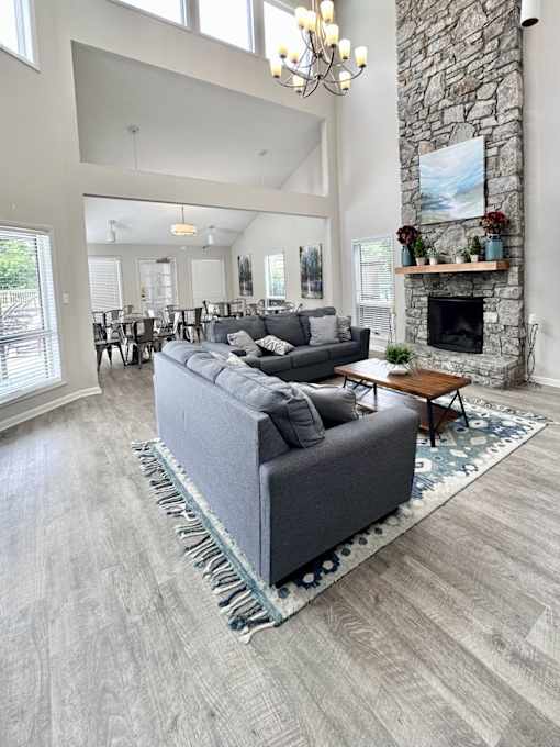A grey couch is in the middle of an apartment clubhouse with a stone fireplace at River Ridge Apartments in Asheville, NC