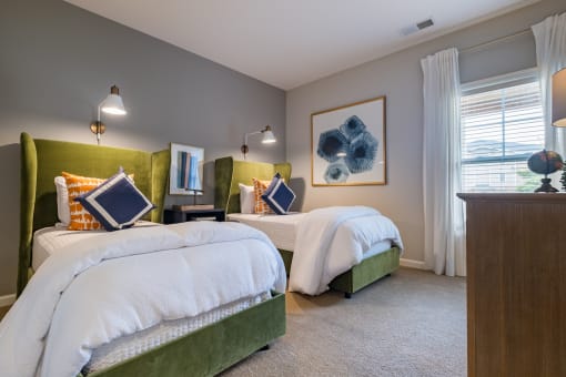 two beds in a bedroom with a dresser and a window