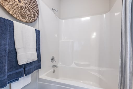 a bathroom with a white tub and a shower and blue towels
