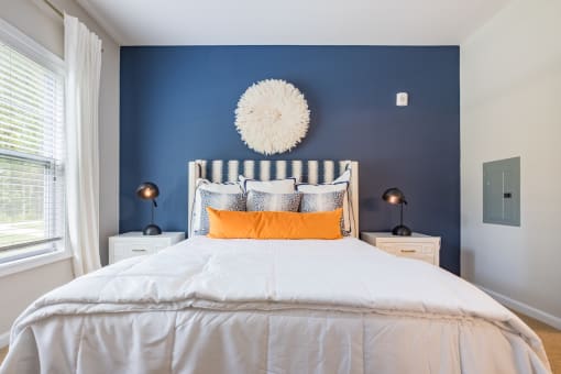 a bedroom with blue walls and a white bed with orange pillows
