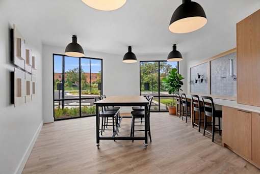 A dining room with a table and chairs and a view of the outside.