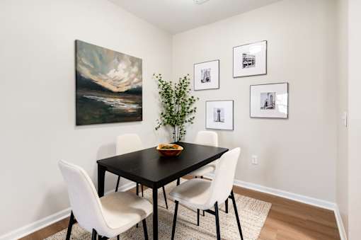 A dining room with a black table and white chairs.