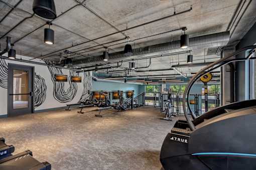 A gym with a row of treadmills and a wall with a black and white design.