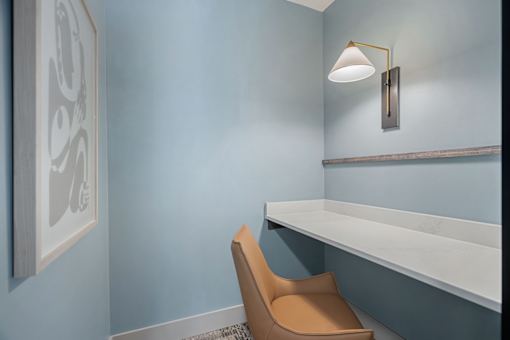 A chair sits in front of a wall with a picture and a shelf.