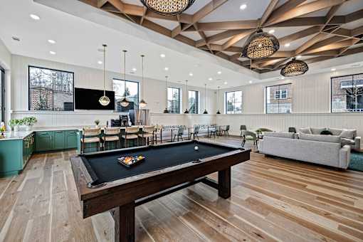 A billiard table is in the middle of a room with a wooden floor and ceiling.