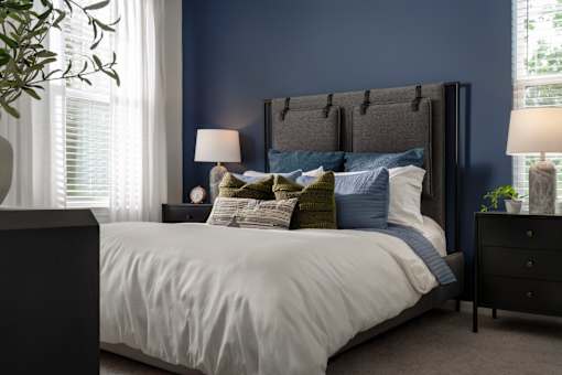 A bed with a white comforter and a dark headboard with pillows on it.