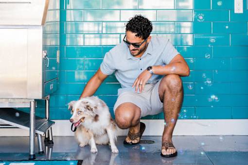 A man with a dog sitting by a pool.