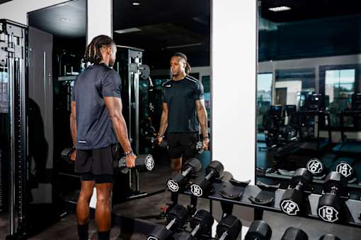A man in a gym is working out with dumbbells.