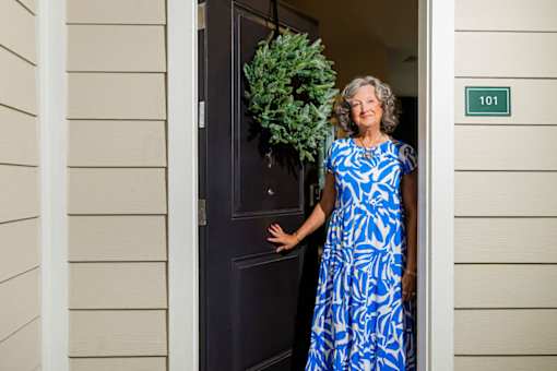 A woman in a blue dress stands in front of a door with a number 101 on it.