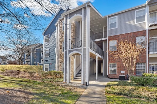 A modern apartment building with a central staircase leading to the upper floors at Heights at New Garden apartments in Greensboro, NC.