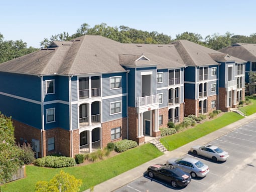 Apartment complex with a parking lot in front.