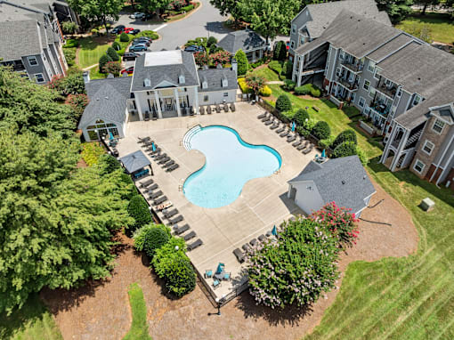A large swimming pool surrounded by a patio and a small garden at Heights at New Garden apartments in Greensboro, NC.