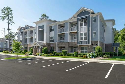 A large apartment complex with a parking lot in front.