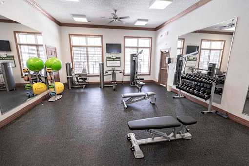 A gym with a variety of equipment including weights and exercise balls.