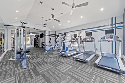 A gym with treadmills, elliptical machines, and other exercise equipment at Heights at New Garden apartments in Greensboro, NC.