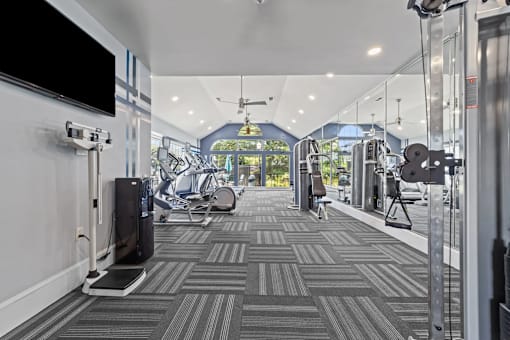 A gym with a treadmill, weights, and exercise equipment at Heights at New Garden apartments in Greensboro, NC.