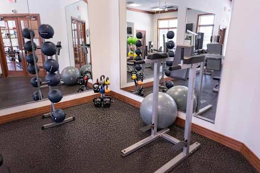 A gym with a mirror, weights, and exercise balls.