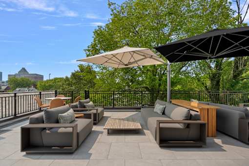 A patio with grey couches and a black umbrella.