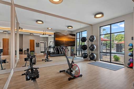 A gym with a variety of exercise equipment including treadmills, stationary bikes, and weightlifting equipment.