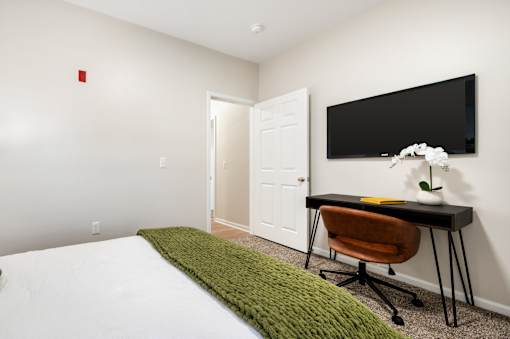 A room with a bed, desk, and chair.