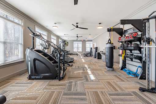 A gym with a variety of equipment including treadmills, weights, and a punching bag.