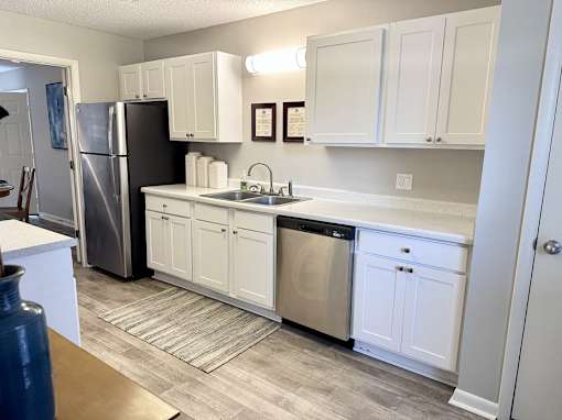 A kitchen with white cabinets and a black refrigerator at River Ridge Apartments in Asheville, NC