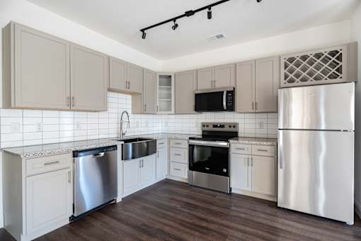 A kitchen with a refrigerator, sink, and oven.