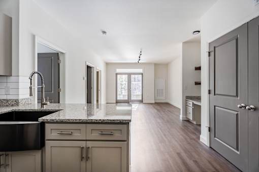 A kitchen with a black counter top and wooden floors.